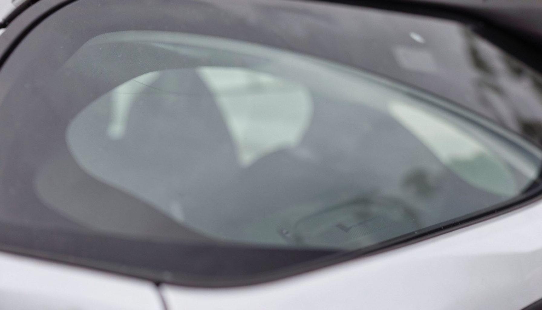 Rear car window with soft reflections, automotive glass detail shot in neutral tones