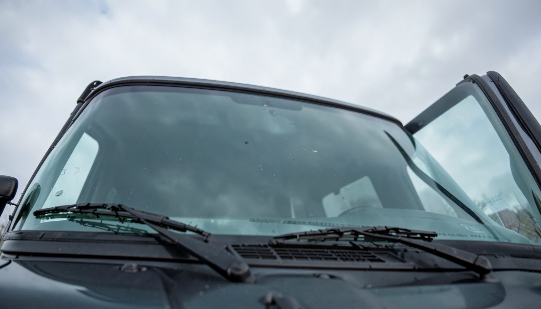 Truck windshield from a low angle, emphasizing size and clarity, overcast sky reflected