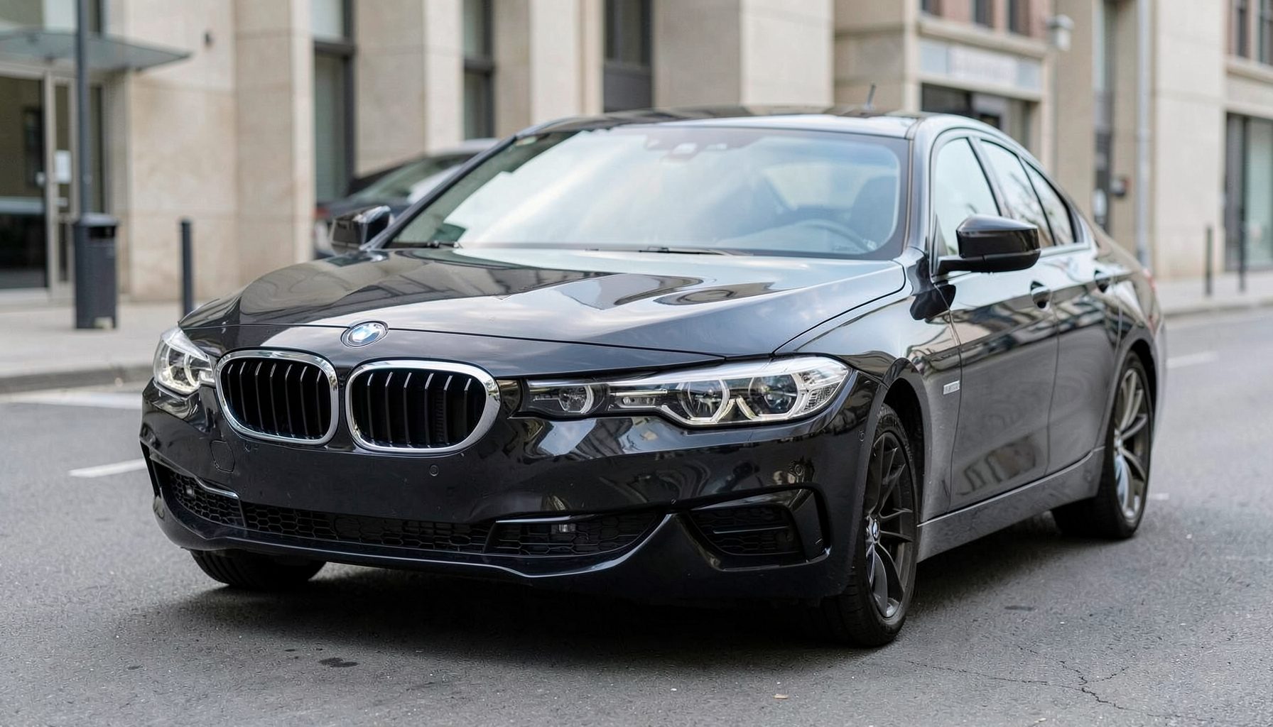 A sleek BMW sedan viewed from the front corner, with a clean windshield reflecting soft daylight against a neutral urban backdrop