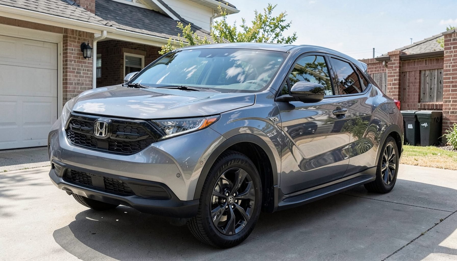 A Honda CRV crossover in a driveway, its large windshield shown from a slight angle with clear sky reflections